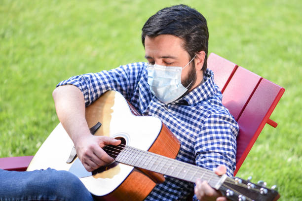 istock Life under Covid-19 - Musician with a mask plays guitar 1224743082