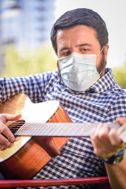 istock Life under Covid-19 - Musician with a mask plays guitar 1224743099