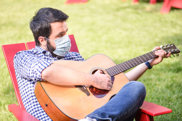 istock Life under Covid-19 - Musician with a mask plays guitar 1224743107