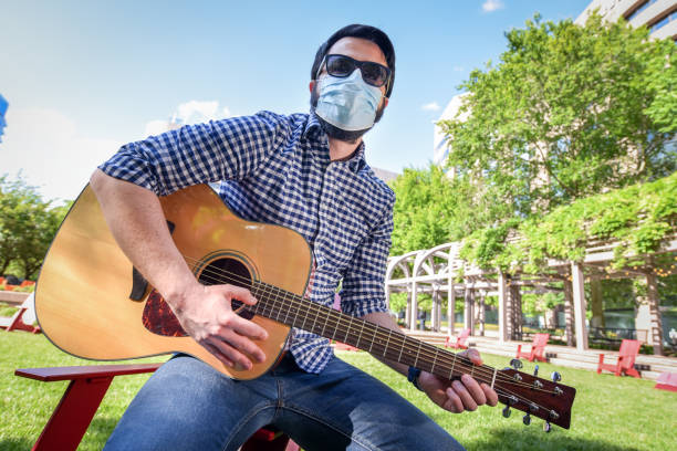 Life under Covid-19 - Musician with a mask plays guitar