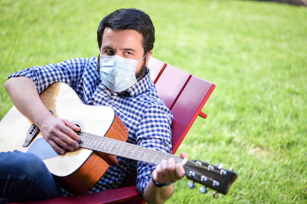 istock Life under Covid-19 - Musician with a mask plays guitar 1224743129