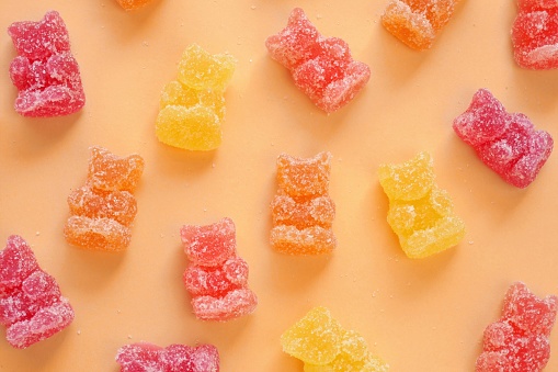 Gummy Bears Jelly Candy. Fruit Bears jelly in sugar background.Candy pattern. Orange, red and yellow jelly bears on a orange background.