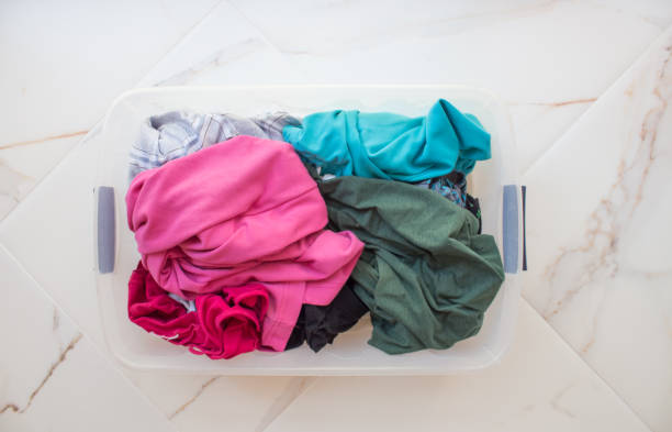 istock Rectangular basket with dirty linen on a white marble floor close-up, top view. Bright underwear of different colors 1224747444