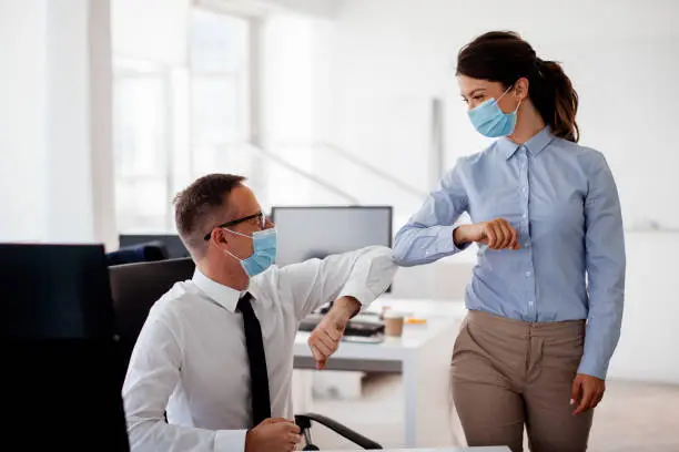 Photo of Business people bump elbows in office for greeting during COVID-19 pandemic stock photo