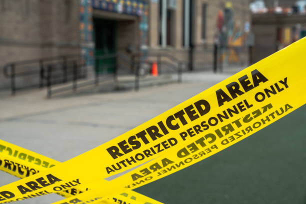 Close up view of an x shaped barrier of yellow restricted area caution tape blocking off a playground at a school in Chicago. stock photo
