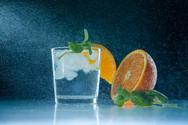 istock Fresh lemonade with mint, orange and ice in a glass jar on a dark blue background. Splashing water splashes. Summer cold drink and cocktail 1224748739