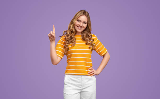 istock Cheerful woman pointing up on lilac background 1224749618