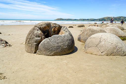 Tourists are walking on Moeraki Boulders beach, Hampden, Otago, South Island, New Zealand.