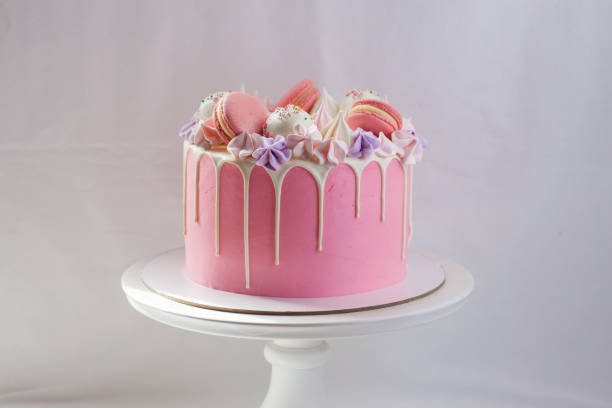 tender pink cake decorated with melted white chocolate, macaroons, meringues, cake pops and candies. plain background. - birthday cupcake pastry baking imagens e fotografias de stock
