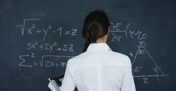 istock Portrait of a beautiful girl, teacher or student solves examples, formulas, triangle on a black board, on a black background 1224757451