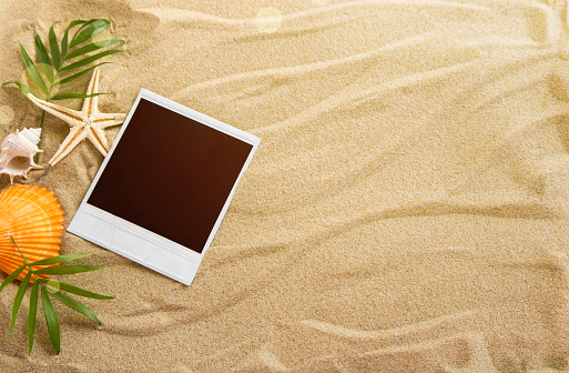 Summer background with a blank instant image on sand