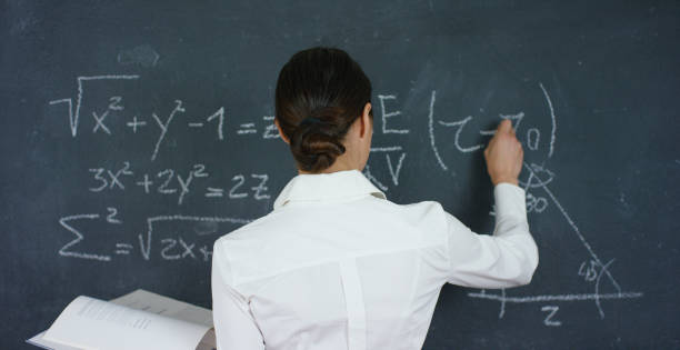 istock Portrait of a beautiful girl, teacher or student solves examples, formulas, triangle on a black board, on a black background 1224757753