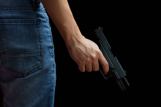 istock Man holding a gun side him on black background. 1224758539