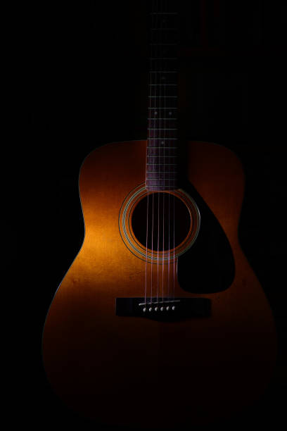 istock Acoustic guitar detail on a black background between light or shadows 1224758569