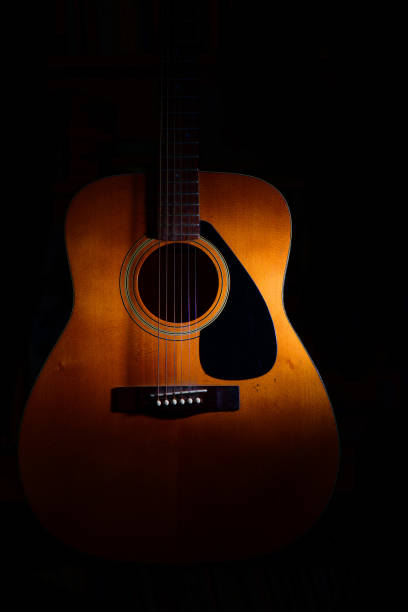 istock Acoustic guitar on a black background between light or shadows 1224758609