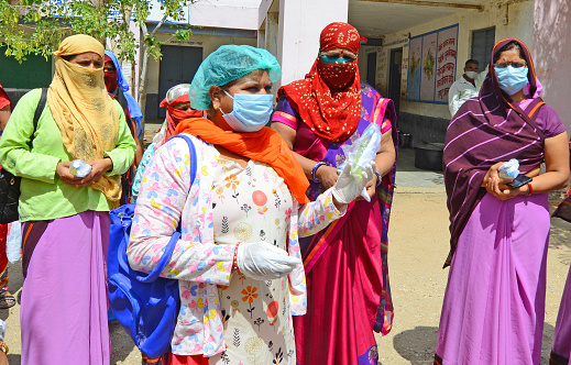 Beawar, Rajasthan, India - May 14, 2020: Anganwadi workers gather to get sanitizer and masks at a government school in Beawar. Anganwadi workers conduct door-to-door health survey to check the spread of novel coronavirus in the city.