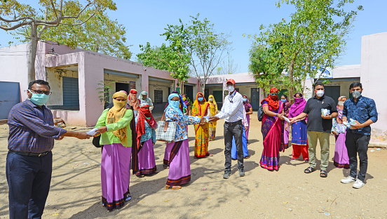 Beawar, Rajasthan, India - May 14, 2020: Municipal councilor and social activist distributes sanitizer and masks to Anganwadi workers at a government school in Beawar. Anganwadi workers conduct door-to-door health survey to check the spread of novel coronavirus in the city.