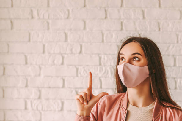 istock Trendy young woman in pink face mask pointing at copy space 1224760596