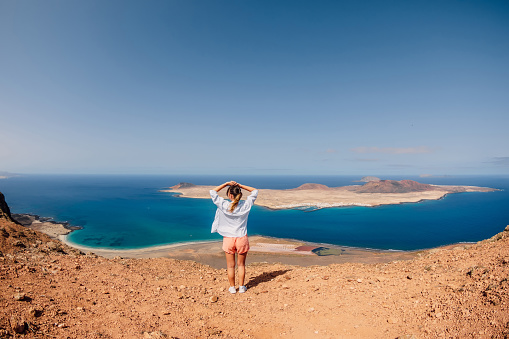 Mirador a La Graciosa desde Lanzarote y mujer viajera feliz. Vista de la isla de La Graciosa y el océano photo