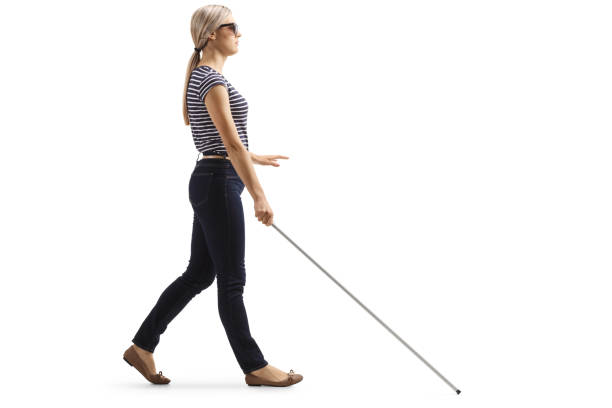 Full length profile shot of a young blind woman walking with a white cane isolated on white background