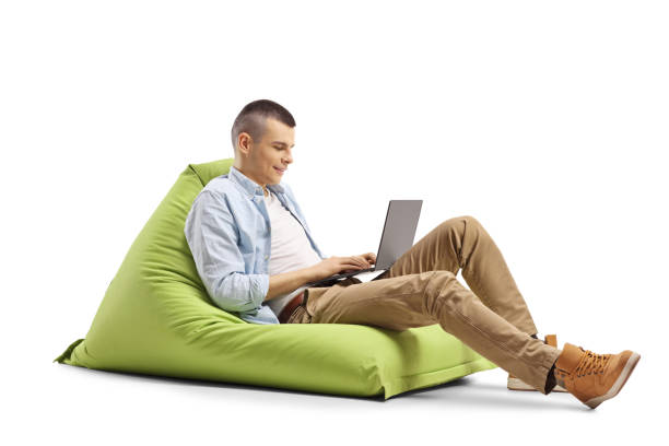 istock Young man working on a laptop and sitting on a green bean bag 1224765778