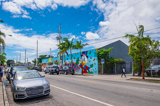 Tourist taking pictures in Wynwood, a former industrial district of Miami redeveloped with colorful murals that cover the walls of many of the buildings.