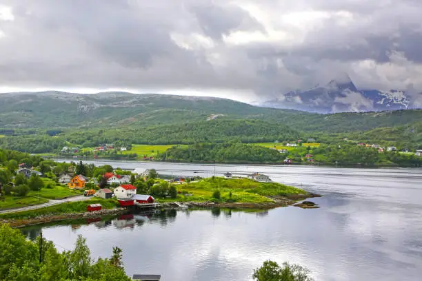Beautiful landscape along with waters edge, with a village & church & mountains in the background, Saltstraumen, Municipality of Bodo, Nordland county, Norway.