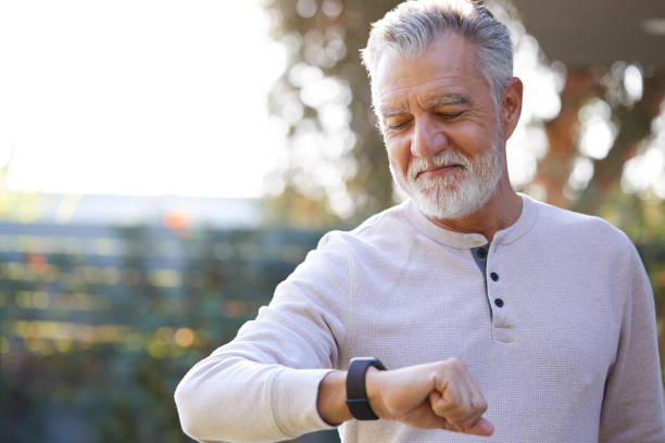 uomo ispanico senior che controlla il monitoraggio della salute su smart watch in giardino a casa - wearable foto e immagini stock