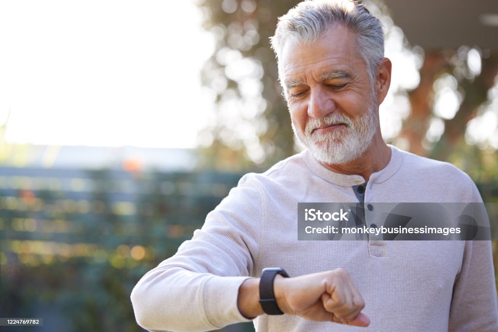 Senior Hispanic Man Checking Health Monitor On Smart Watch In Garden At Home Smart Watch Stock Photo