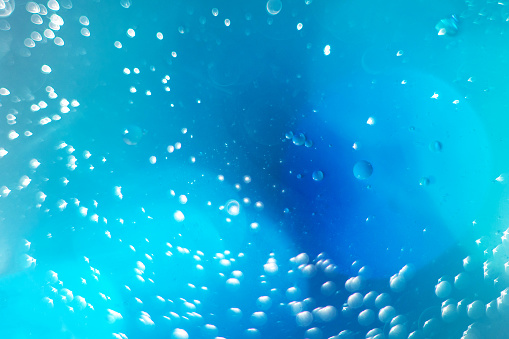 Macro fluid with bubbles, abstract blue background. Selective focus.