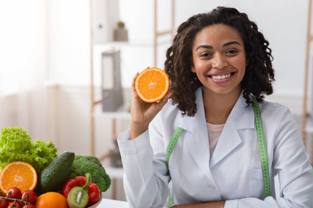 istock Cheerful female dietician holding fresh orange half 1224771676
