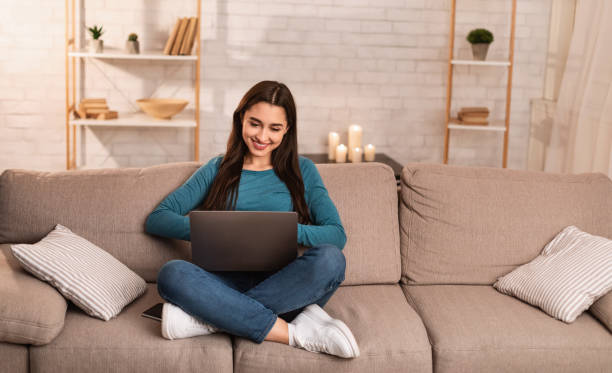 istock Woman using her laptop sitting on sofa 1224771693