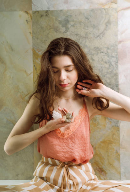 mujer sentada en el suelo sosteniendo varias piedras de cristal en sus manos - quartz caucasian one person energy fotografías e imágenes de stock