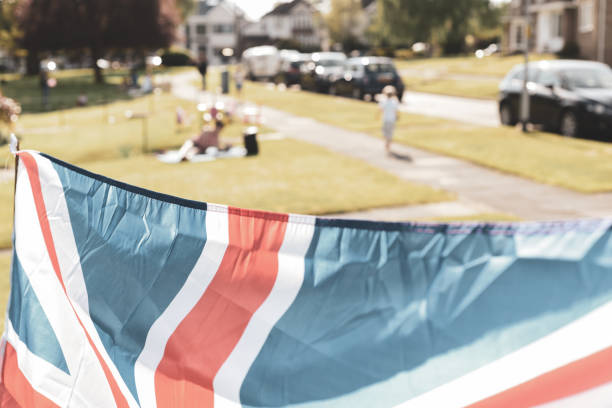 Vintage style Union Jack flag flying in front of VE Day celebrations at a social distance street party in May 2020 Vintage style Union Jack flag flying in front of VE Day celebrations at a social distance street party in May 2020 ve day celebrations uk stock pictures, royalty-free photos & images