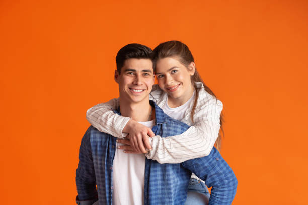 istock Young smiling guy holds girl on his back 1224774345