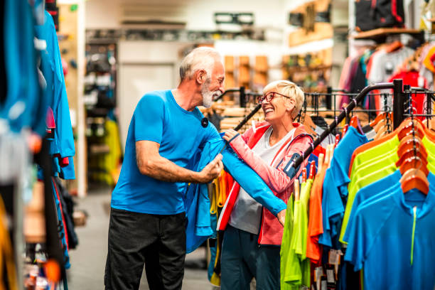 istock Senior male putting on a soft shell hiking jacket while his partner is standing by in a mountaineering equipment store 1224776293