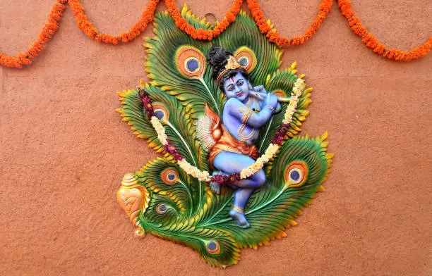 Photo of Close-up of wall art of Indian Hindu God Krishna playing bansuri or musical instrument