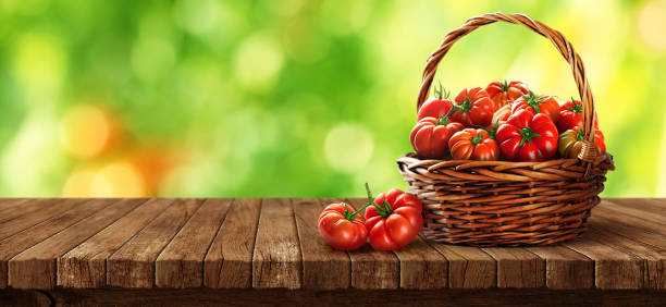 Freshly tomatoes in a basket on a wooden table stock photo