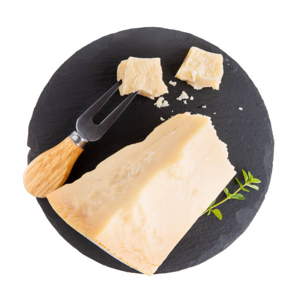 Piece of parmesan cheese on black slate board  isolated on white. Parmigiano Reggiano, hard mature cheese. Top view. Piece of parmesan cheese on black slate board  isolated on white. Parmigiano Reggiano, hard mature cheese. Top view. grana padano stock pictures, royalty-free photos & images