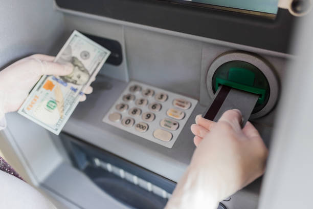 istock Hands in protective surgical gloves holding one hundred dollar bill and using credit card at atm banking device. Covid-19 concept. 1224779437
