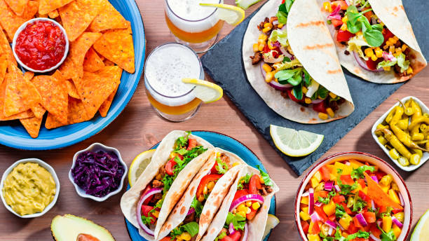 istock Table with tacos, mango salsa, nachos with sauce, guacamole, lemon beer for Cinco de Mayo celebration party. Appetizers and traditional mexican dishes for family dinner on wooden table top, copy space 1224780577