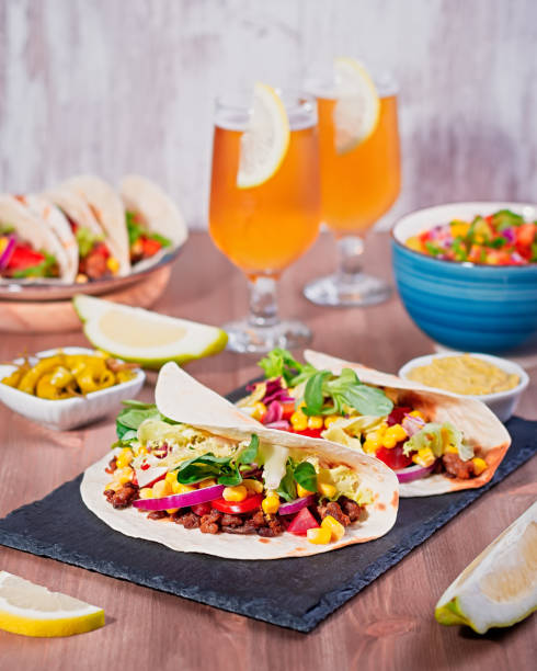 istock Table with tacos, mango salsa, nachos with sauce, guacamole, lemon beer for Cinco de Mayo celebration party. Appetizers and traditional mexican dishes for family dinner on wooden table top, copy space 1224780592