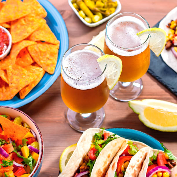 istock Table with tacos, mango salsa, nachos with sauce, guacamole, lemon beer for Cinco de Mayo celebration party. Appetizers and traditional mexican dishes for family dinner on wooden table top, copy space 1224780595