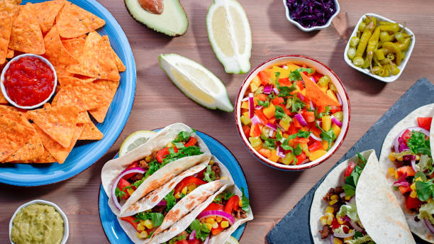istock Table with tacos, mango salsa, nachos with sauce, guacamole, lemon beer for Cinco de Mayo celebration party. Appetizers and traditional mexican dishes for family dinner on wooden table top, copy space 1224780600