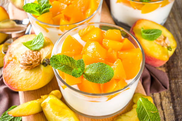 Curd or yogurt dessert with canned and fresh peaches, on wooden rustc background. Summer breakfast fruit dessert.