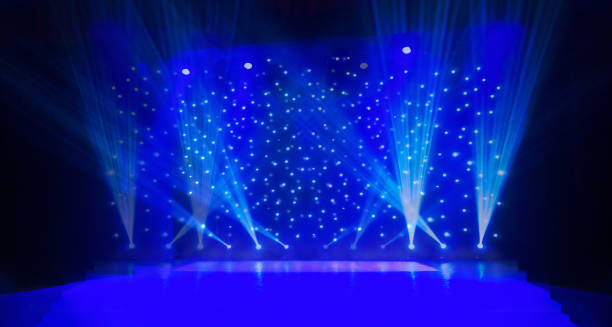 istock Blurred show background. Empty stage and sparkling stage lights. Blue light beams spotlights on stage at time of entertainment show. Laser and lights show in the dark 1224783488