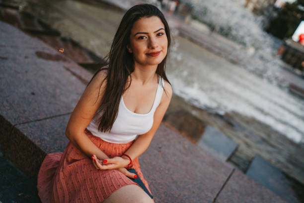 Beautiful young woman relaxing by city fountain