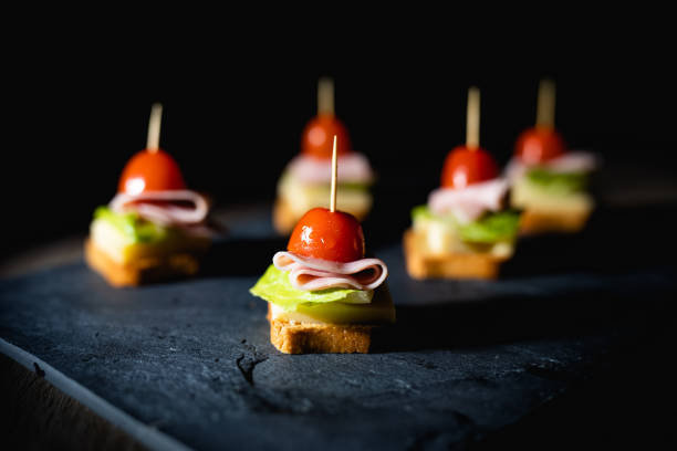 świeże przekąski z tostami, sałatą, szynką i pomidorem wiśniowym na kamiennej desce z ciemnym tłem - cherry tomato flash zdjęcia i obrazy z banku zdjęć