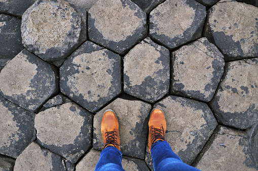 An image of feet standing upon basalt columns of Giant's Causeway in Northern Ireland