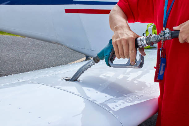 nahaufnahme eines flugzeugarbeiters, der ein propellergetriebenes flugzeug mit niedrigem flügel betankt - small airplane air vehicle propeller stock-fotos und bilder